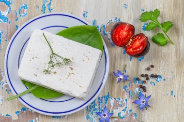 Kırpma yolu ile beyaz arkaplanda izole edilmiş Feta peyniri küpleri. Feta peyniri, fesleğen yaprağı ve domates yığını..