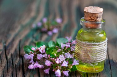 Şişede kekik yağı ve taze çiçekler. Doğal kozmetik ve aroma terapisi.