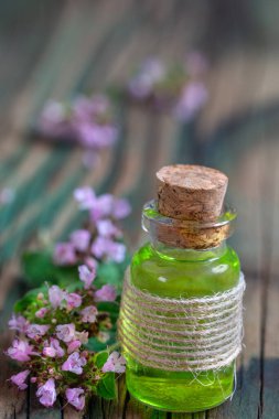 Şişede kekik yağı ve taze çiçekler. Doğal kozmetik ve aroma terapisi.