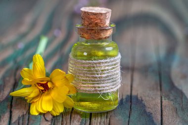 Calendula çiçekleri ve kehribar bardaktan yağ dökülüyor. Kadife çiçeği, bitkisel ilaç, naturopati ve fizyoterapi..