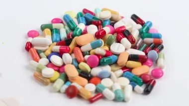 Masada çok sayıda renkli tablet var. Beyaz arkaplanda çok sayıda hap var.