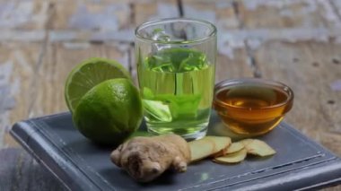 Zencefilli bitki çayı. Bir bardak limonlu zencefil çayı, bal ve bej üzerine nane ve ahşap masa arkaplanı. Alternatif tıp kavramı, doğal ev yapımı.