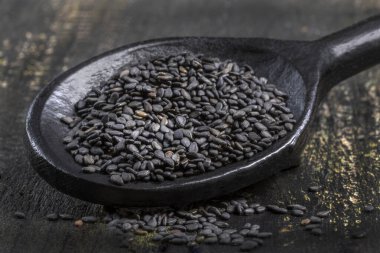 Tahta tahtadaki tahta kaşıkta siyah susam taneleri.