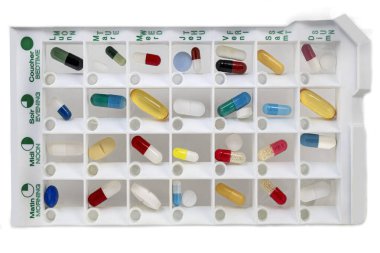 A weekly pill organizer is neatly arranged with multiple compartments filled with different colored capsules and tablets for daily medication adherence. Each section is clearly marked for easy access. clipart