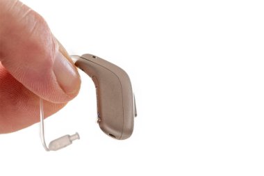 A hand carefully holds a small hearing aid, showcasing its lightweight design and fine details. This device enhances auditory experiences for individuals with hearing challenges. clipart