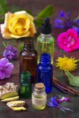 Çeşitli önemli yağ şişeleri taze çiçek ve otların arasında oturur, kırsal ahşap bir yüzeyde doğal güzellik ve refahı ön plana çıkaran renkli bir çeşitlilik sergiler..