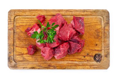 Köy ahşap bir kesme tahtasının üzerinde maydanozla süslenmiş taze et parçaları düzenlenir. Sıhhatli bir yemek hazırlamak için verilen ipuçları.