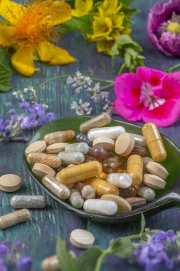 Çeşitli renkli besin maddeleri canlı çiçeklerle çevrili koyu yeşil bir kaşığa yerleştirilmiştir. Bu görüntü, beslenme meraklıları için mükemmel sağlık ve sağlık temalarını vurgular..