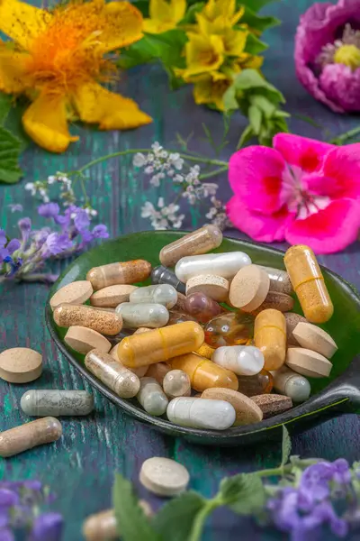 Çeşitli renkli besin maddeleri canlı çiçeklerle çevrili koyu yeşil bir kaşığa yerleştirilmiştir. Bu görüntü, beslenme meraklıları için mükemmel sağlık ve sağlık temalarını vurgular..