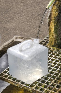 Dikdörtgen şeklinde bir buz kütlesi, üzerine su akarken yavaşça erir. Kurulumda, buzun altında doğal bir çevreyle çevrili metal bir ızgara bulunan taş bir çeşme yer alıyor..