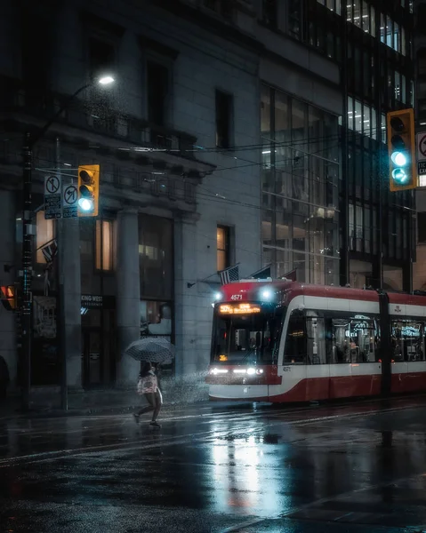 Kadınlar Toronto tramvayı önünde şemsiyeyle karşıdan karşıya geçiyorlar