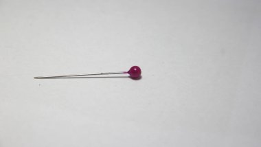 Basit bir arka planda kıyafet ve moda temalı dikiş için tek bir iğne. Yatay kenar görünümü.