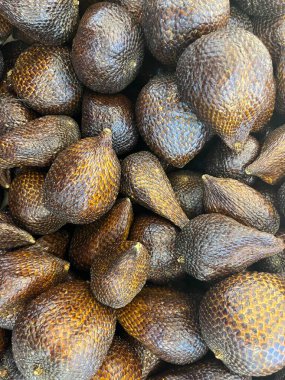 Endonezya 'da kahverengi, sivri derili yılan meyvesi ya da buah salak denir. Geleneksel pazar fotoğrafçılığında lezzetli, tatlı ve sağlıklı meyve yığını. Açık sarı meyve eti ve içinde büyük bir kahverengi tohum..