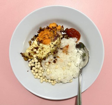 Endonezya usulü yemek menüsü. Ilık beyaz pirinç, telor ceplok ya da sambal bawang biberli yumurta, çerez. Düşük bütçeli ama pembe arka planda izole edilmiş lezzetli bir yemek. Makanan rumahan.