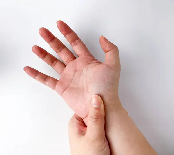 Light skin toned human hand with massaging hand wrist pose gesture. Carpal tunnel syndrome themed photography isolated on white studio background.