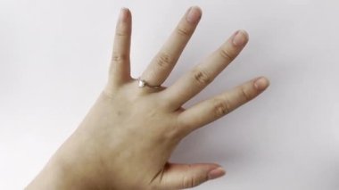 Elin yüzük parmağından gümüş elmas yüzüğü çıkarıp masaya fırlatıyor. Yatay beyaz arkaplanda izole edilmiş boşanma veya ayrılma konsepti görüntüleri.