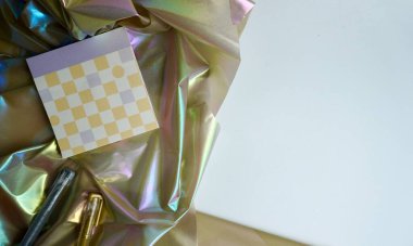 Kare kareli tasarım mor ve sarı kağıt. Yatay arkaplanda izole edilmiş parlak kumaş bezinin üzerinde gümüş ve altın renkli jel kalem var..