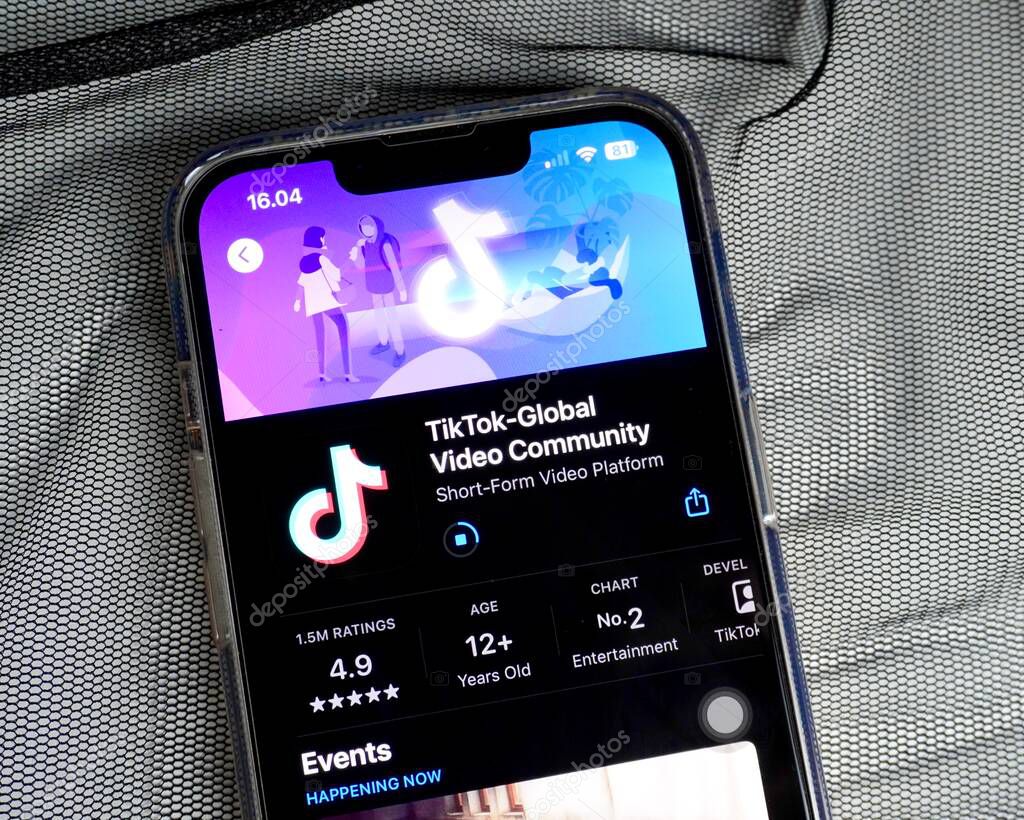 Jakarta, Indonesia - April 22th, 2024 - Tiktok global video community sharing in app store. Mobile application on Iphone 13 smartphone body isolated on transparent thin black fabric background.