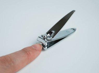 İnsan parmağı paslanmaz çelik krom demir üzerinde küçük seyahat boyutunda tırnak makası ya da makas. Nesne fotoğrafçılığı beyaz arkaplanda izole edildi.