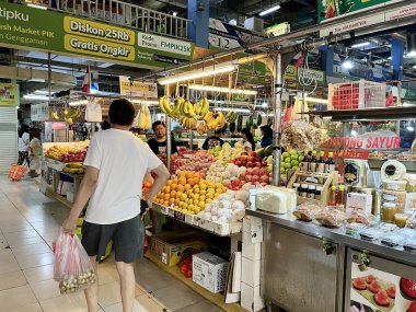 Jakarta, Indonesia - May 24th, 2024 - Indoor fresh market fruit bazaar display store with a few buyers and sellers isolated on horizontal ratio indoor market stall background. clipart