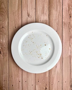 Ekmek, bisküvi ya da beyaz tabağın üstünde çıtır çıtır ekmek kırıntıları. Tatlı temalı görüntüyü yemeyi bitirdim. Dikey orantılı tahta yüzey arkaplanında nesne fotoğrafçılığı izole edildi.