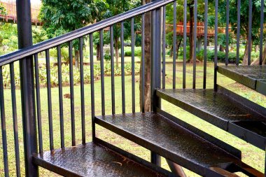 Siyah metal merdiven, el parmaklıkları ile kapalı yatay oran dış park arka planı ile yürüyüş.