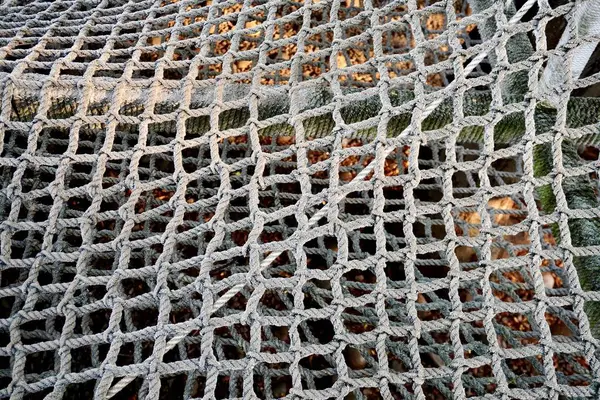 stock image Thick rope with net pattern isolated on outdoor park playground horizontal ratio dry brown fallen leaves on ground background.