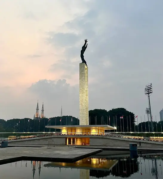 Jakarta, Endonezya - 11 Temmuz 2024 - Lapangan Banteng Parkı 'nda ışıklarla birlikte Monumen patung pembebasan irian barat. Düzenleyici nesne fotoğrafçılığı dikey arkaplanda izole edildi.