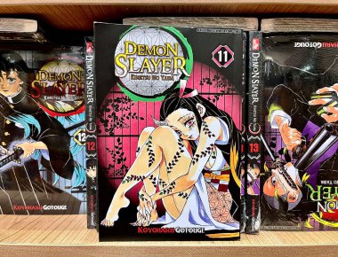 Jakarta, Endonezya - 18 Temmuz 2024 - İblis Avcısı veya Kimetsu No Yaiba manga cilt 11. Gramedia kitapçısındaki çizgi roman kapağı ahşap raf yatay oran arkaplanı izole.