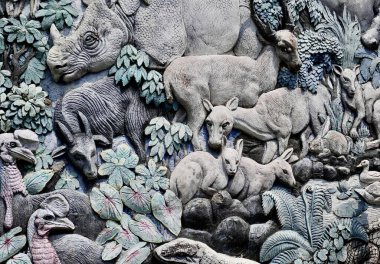 Jakarta, Indonesia - July 24th, 2024 - Rhino, komodo, and mousedeer wild animal pattern carving design isolated on horizontal stone wall background. clipart