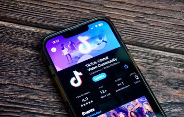 Jakarta, Endonezya - 7 Ağustos 2024 - Uygulama mağazasındaki Tiktok global video topluluğu mobil uygulama ekranı yatay oran kahverengi tahta yüzey arka planında izole edildi.