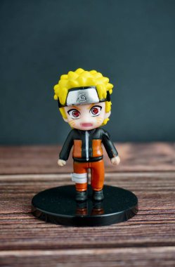 Jakarta, Endonezya - 7 Ağustos 2024 - Naruto uzumaki küçük chibi tarzı gacha ödül oyuncağı dikey ahşap masa ve siyah duvar yüzeyi arka planında izole edildi.