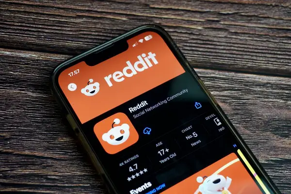 stock image Jakarta, Indonesia - August 7th, 2024 - Reddit mobile application screen on app store isolated on horizontal ratio brown wooden surface background.