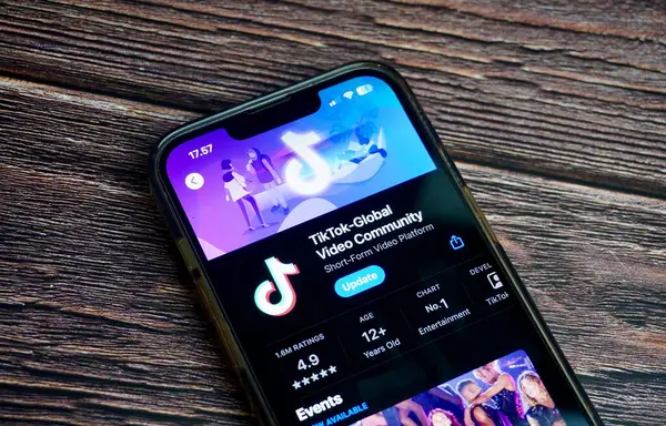 Jakarta, Endonezya - 7 Ağustos 2024 - Uygulama mağazasındaki Tiktok global video topluluğu mobil uygulama ekranı yatay oran kahverengi tahta yüzey arka planında izole edildi.