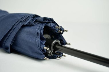 Koyu mavi katlanabilir küçük şemsiye fotoğrafçılığının yatay beyaz arkaplanda izole edilmiş bir kısmını kapat.