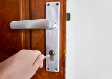 Kapı tokmağını açmak için el ele tutuşun. Yatay kahverengi arka planda izole edilmiş..