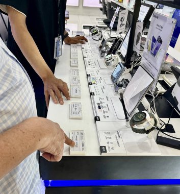 Jakarta, Endonezya - 26 Ağustos 2024 - Samsung Galaksi Saati, tomurcukları ve akıllı telefon ürünleri vitrinine bakan müşteri kapalı mekan arka planında izole edildi.