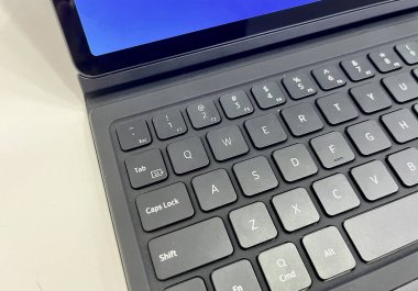 Tablet gri renkli klavyeye bağlı. Modern aygıt yatay beyaz masa arkaplanında izole edildi.