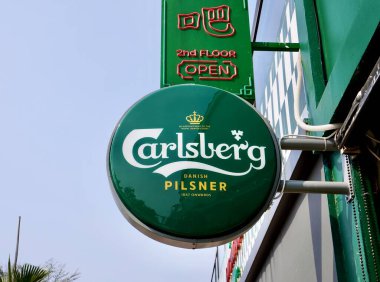 Jakarta, Endonezya - 19 Eylül 2024 - Carlsberg Danimarka Pilsner 1847 yuvarlak yeşil levha levhaları açık hava mavi gökyüzü ve dış arkaplan inşa.