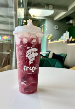 Jakarta, Endonezya - 21 Kasım 2024 - Meyve suyu soğuk içeceği plastik bardakta dikey oranda kapalı masa içi beyaz arka planda izole edildi.