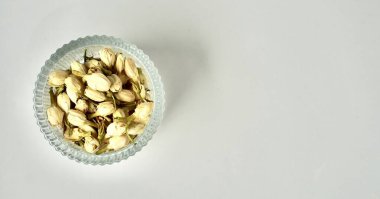 Kurumuş yasemin çiçeği tomurcukları aromateryaller ve yuvarlak cam kasede çay malzemeleri yatay fotokopi aralığında izole edilmiş düz bir arkaplan..