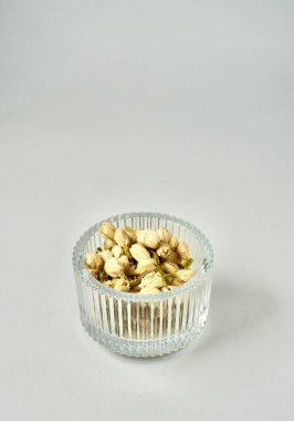 Kurumuş yasemin çiçeği tomurcukları aromaterapi için ve cam kasedeki çay malzemeleri dikey kopyalanmış düz arkaplanda izole edilmiş..