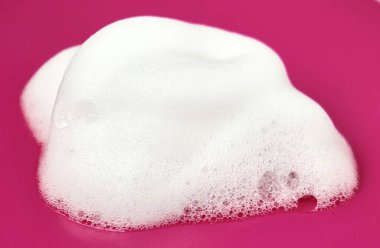 Köpüklü el yıkama kumaşı, yatay pembe arka planda izole edilmiş..