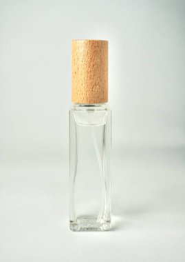 Deri bakımı ya da parfüm şeffaf cam sprey şişesi. Dikey beyaz arka planda kahverengi ahşap kapaklı..