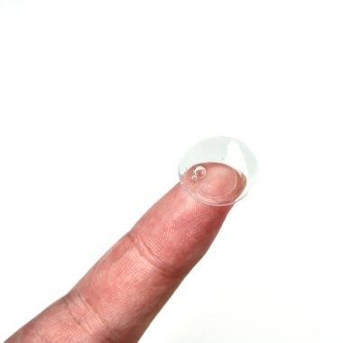 Kare beyaz arkaplanda izole edilmiş parmak ucundaki açık bir kontakt lens nesnesi.