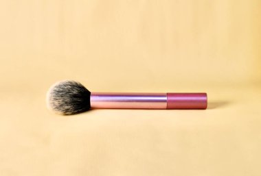 Yatay kahverengi krem rengi arka planda izole edilmiş pembe saplı allık makyaj fırçası.