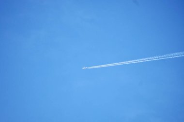 Beyaz duman çizgileri olan hızlı uçak açık mavi gökyüzünde izole edilmiş açık hava arka planında.