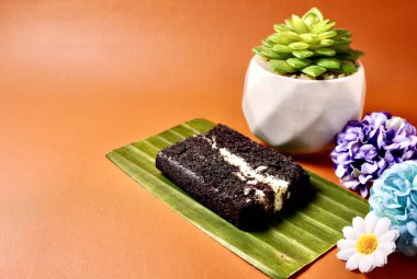 Muz yaprağının üzerinde Bolu ketan hitam keki. Endonezya geleneksel jadana pasar tatlısı yatay fotokopi arkaplanda izole edilmiş kaktüs ve çiçek dekoru ile.