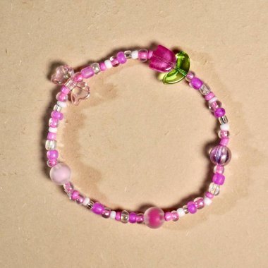 Şirin pembe boncuk bilezik aksesuarları. Kare kahverengi krem rengi arka planda izole edilmiş..