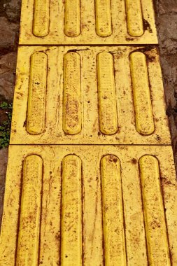 Dikey oran parkı kaldırım zemininde kirli toprak lekesi olan sarı kabartma yazılar..